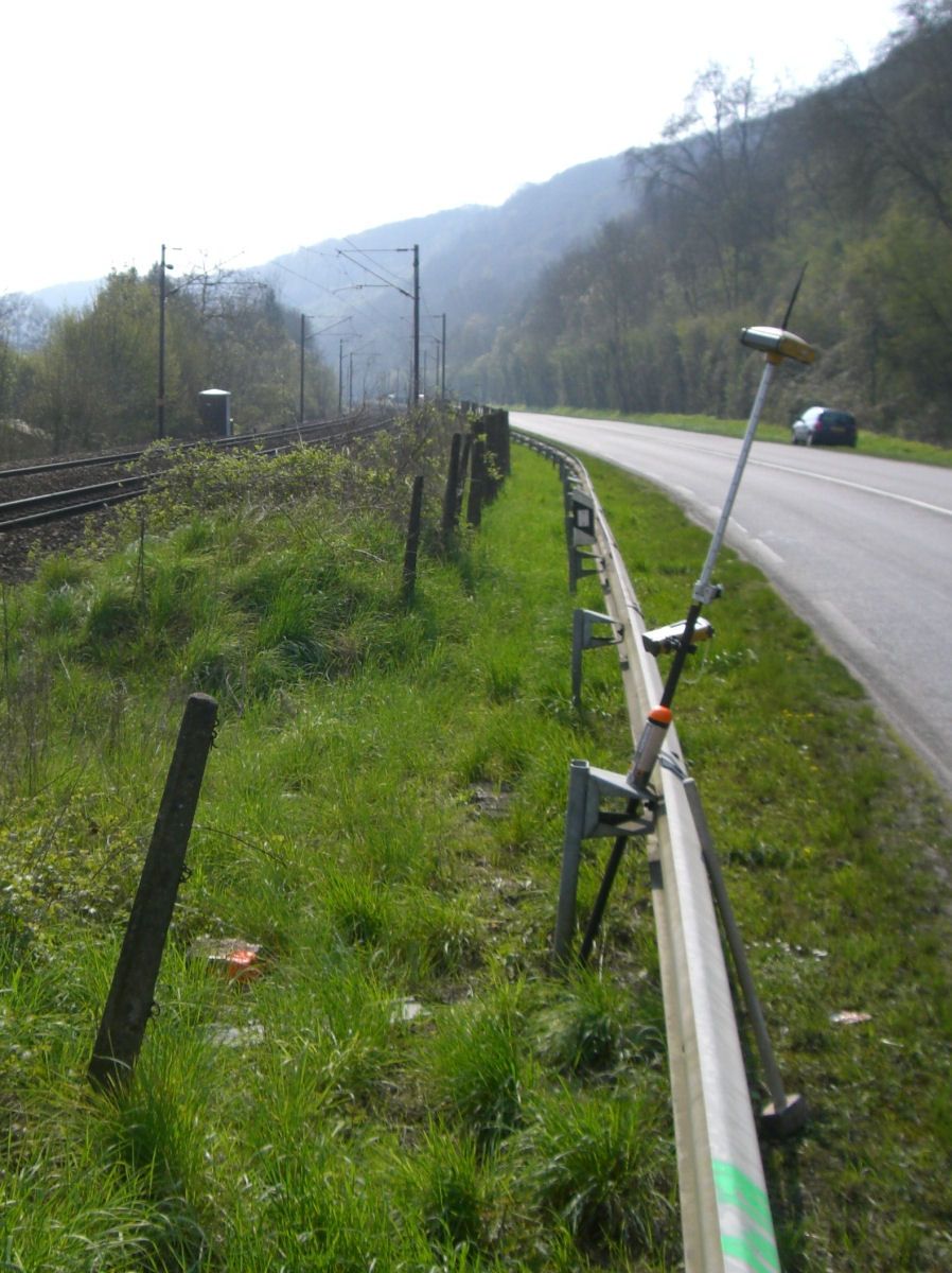 Canne GNSS en station le long d'une route départementale bordée d'une voie ferrée
